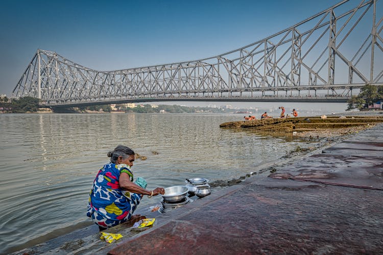 Woman Washing Dishes In Hooghly River 