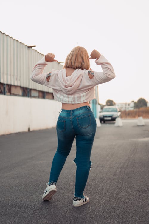 Woman with big buttocks in tight pants stands by the road with smartphone  in her hand Stock Photo