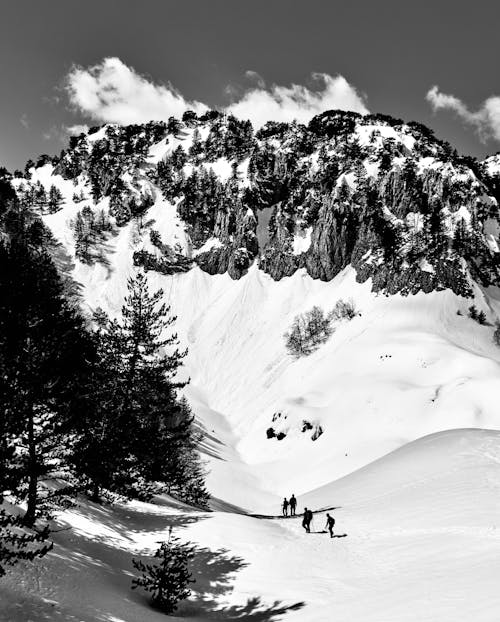 A Grayscale Photo of People Hiking on Snow Covered Mountain