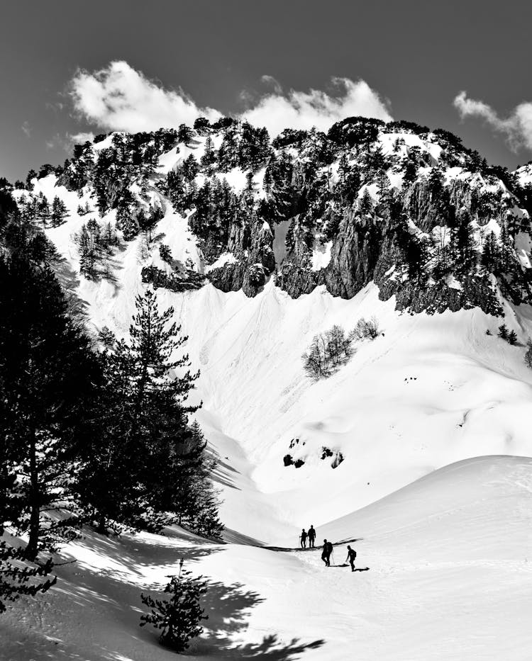 A Grayscale Photo Of People Hiking On Snow Covered Mountain