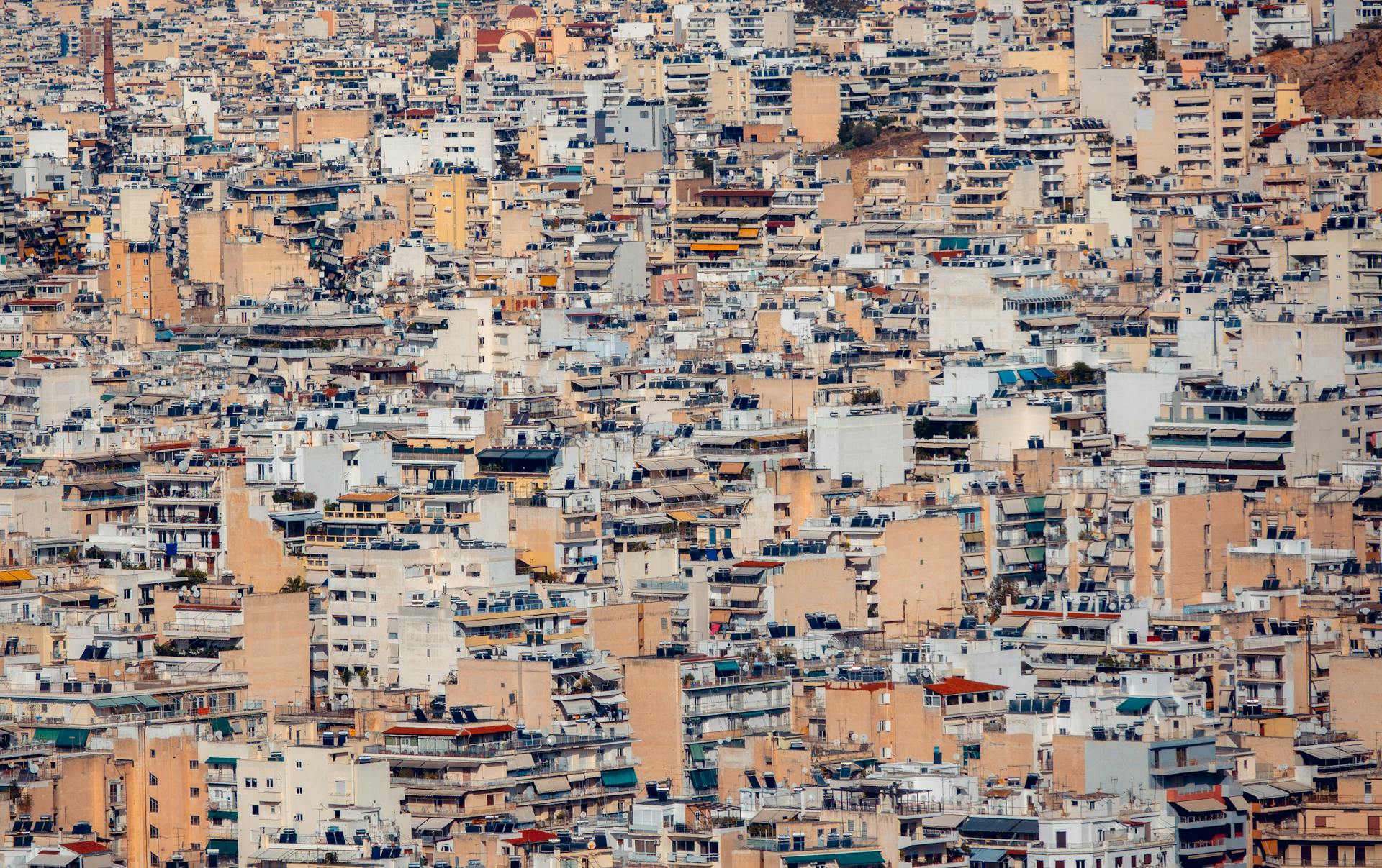 Expansive view of densely packed rooftops and buildings in Athens, Greece showcasing urban architecture.