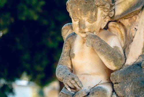 Free Detailed close-up of a weathered cherub statue showcasing intricate carvings and natural aging. Stock Photo