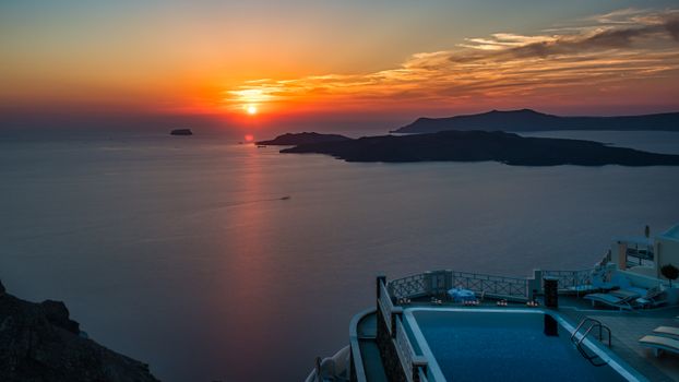 Stunning sunset view over the Aegean Sea from Thira, Santorini with a poolside foreground.