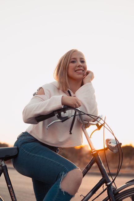 A smiling woman on a bicycle enjoying a relaxing sunset ride outdoors.