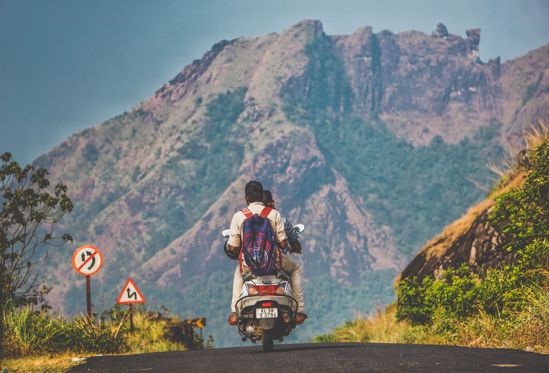 Two people on a scooter enjoying a scenic motorcycle ride through a mountain road.