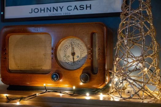 A classic wooden radio adorned with decorative string lights and a retro poster backdrop.