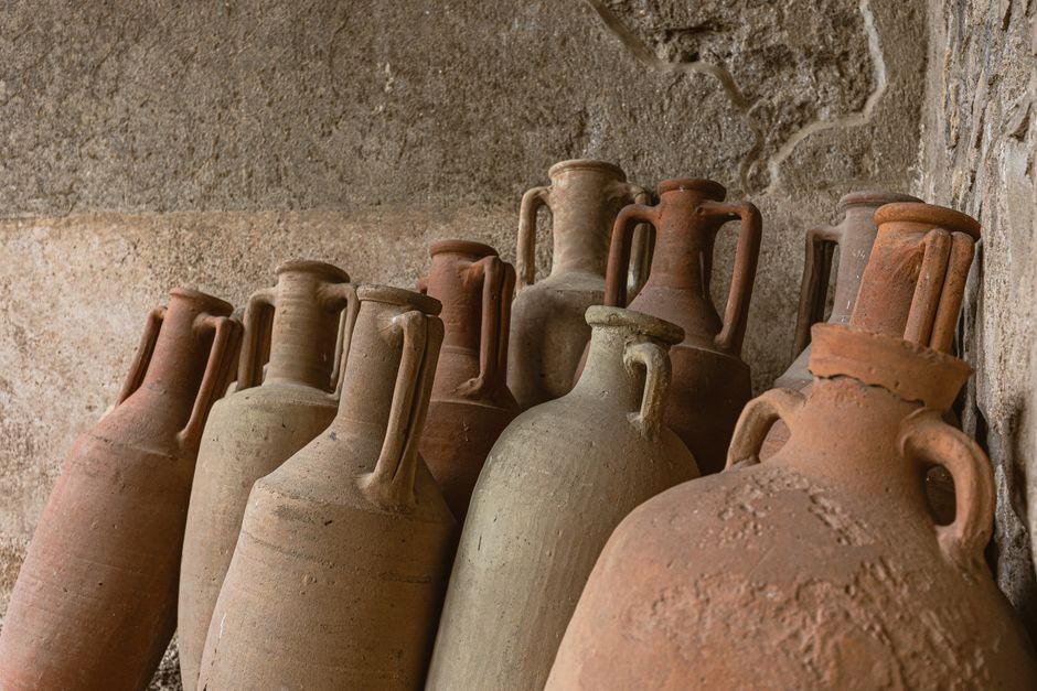 Rustic clay jars arranged against a textured stone wall, showcasing ancient craftsmanship.