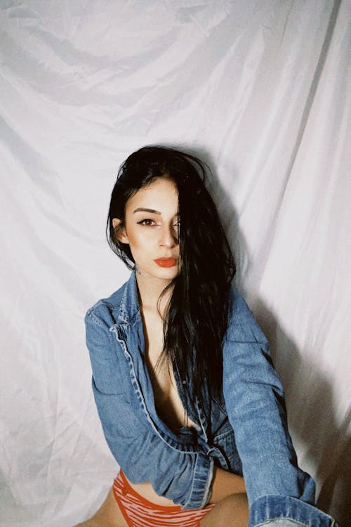 Woman in Denim Jacket and Pantie  Sitting Beside a White Blanket