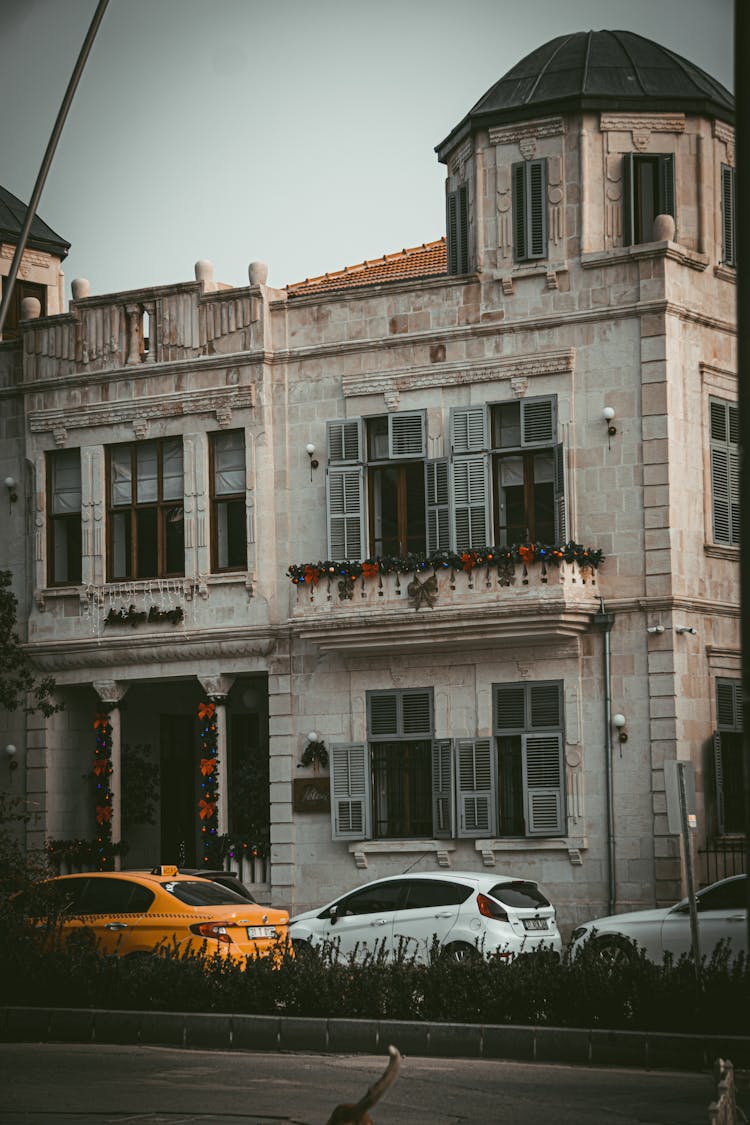 A White Concrete Building Near A Street With Cars