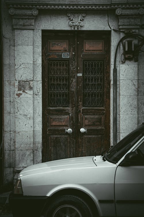 White Car Parked in Front of an Wooden Entrance Door 