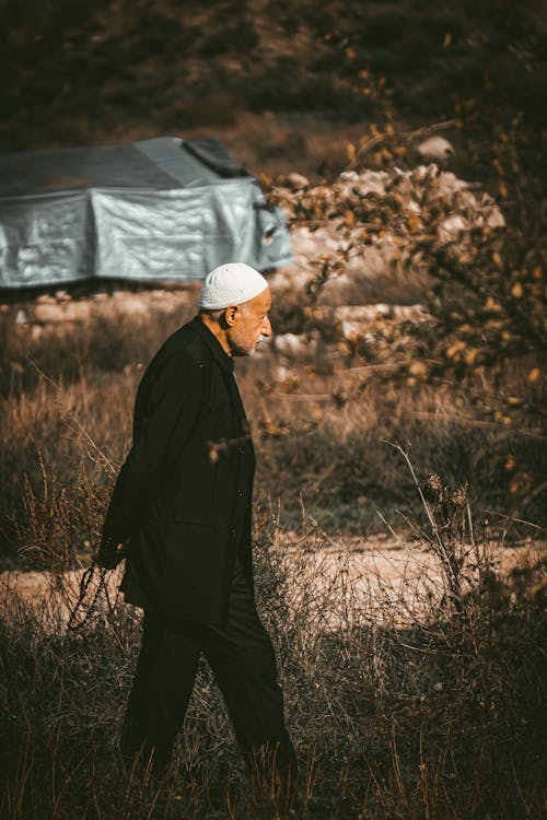 Elderly Man in a Black Suit Walking on a Field 