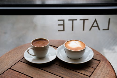 An Espresso and a Cappuccino on a Table in a Cafe 