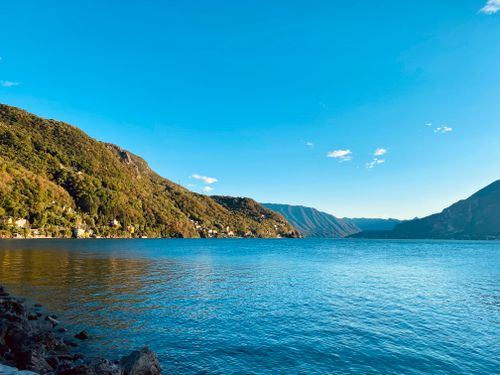 Free Breathtaking view of a tranquil mountain lake with lush green hills and a vivid blue sky. Stock Photo