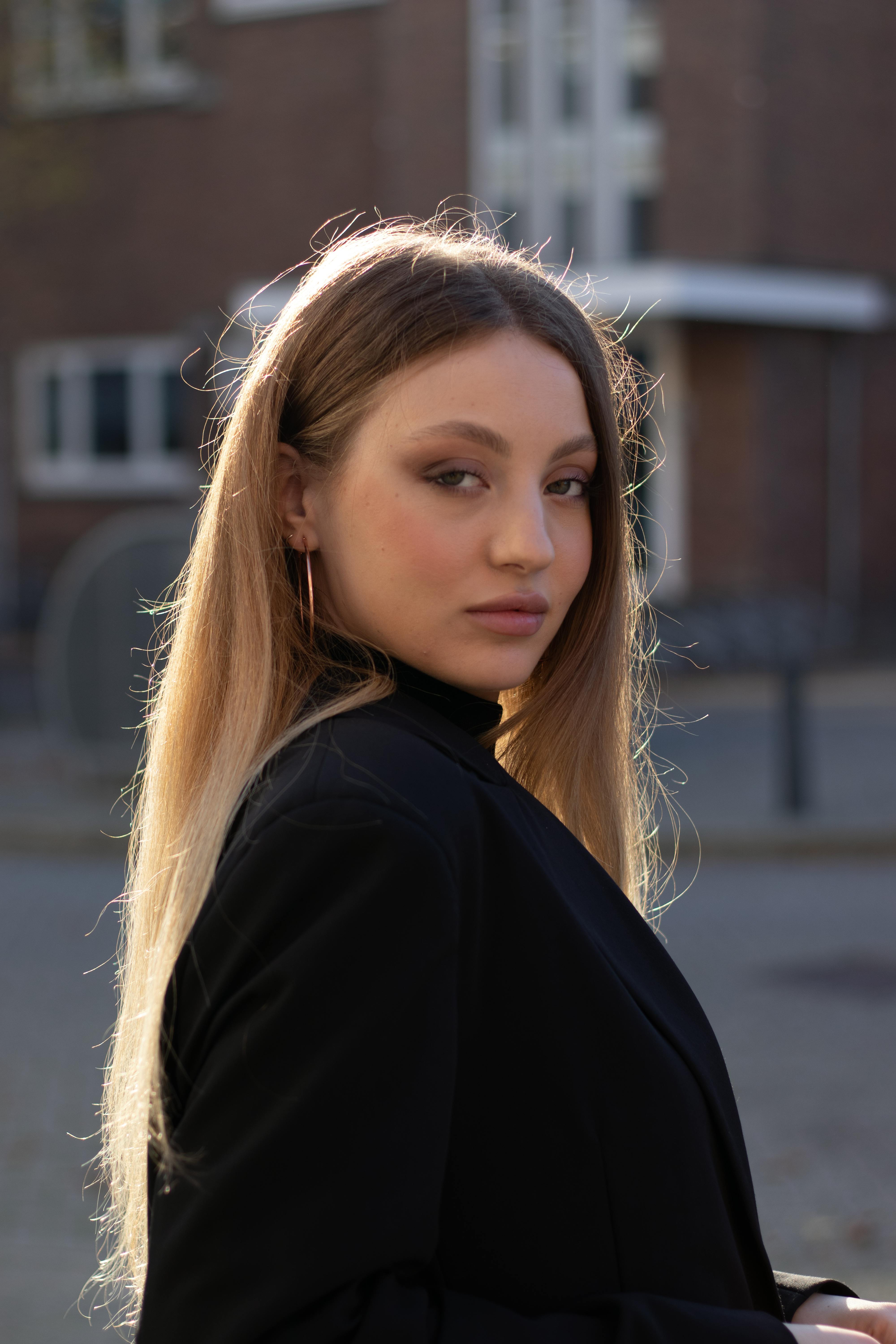 Stylish young woman in Rotterdam, highlighting her elegance with a city backdrop.
