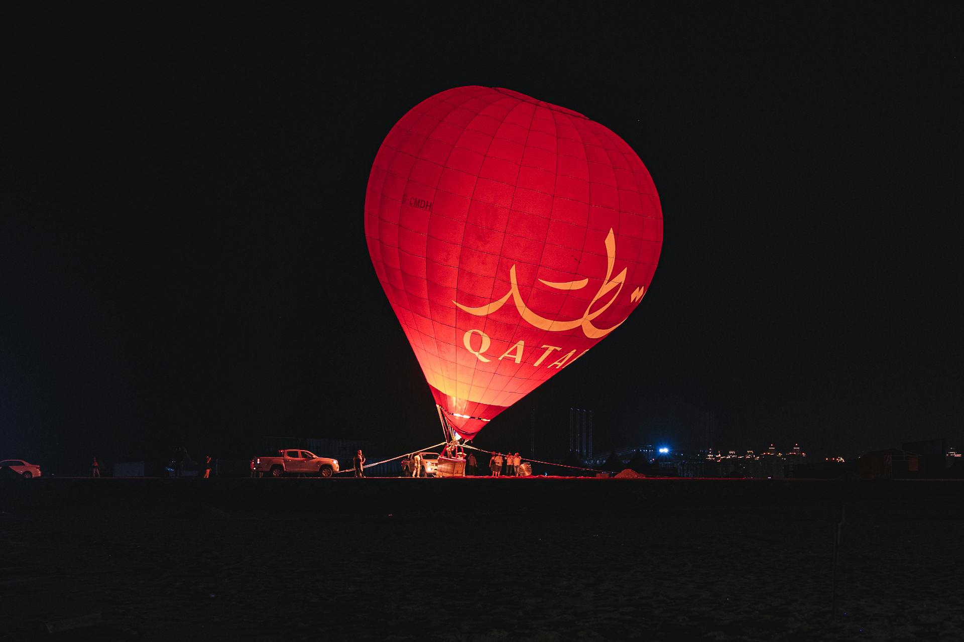 A striking red hot air balloon lights up the Qatari night sky, adding to the desert's allure.