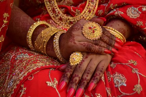 Free Close-up of hands adorned with ornate mehndi and traditional gold jewelry in a cultural setting. Stock Photo