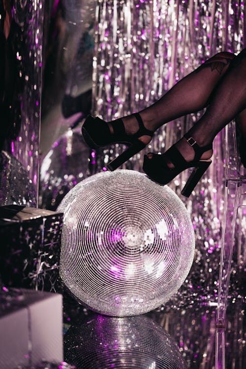 A Person Wearing Black High Heels Stepping on the Disco Ball in a Nightclub