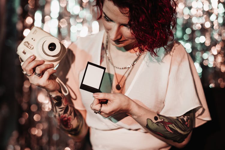 Woman Holding A Polaroid Camera And Looking At The Picture 