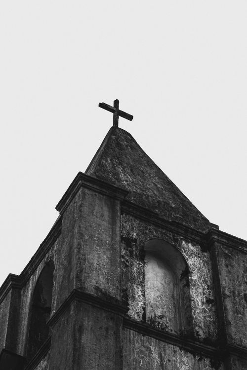Free A grayscale image of an ancient church tower with a cross against the sky in São Paulo, Brazil. Stock Photo