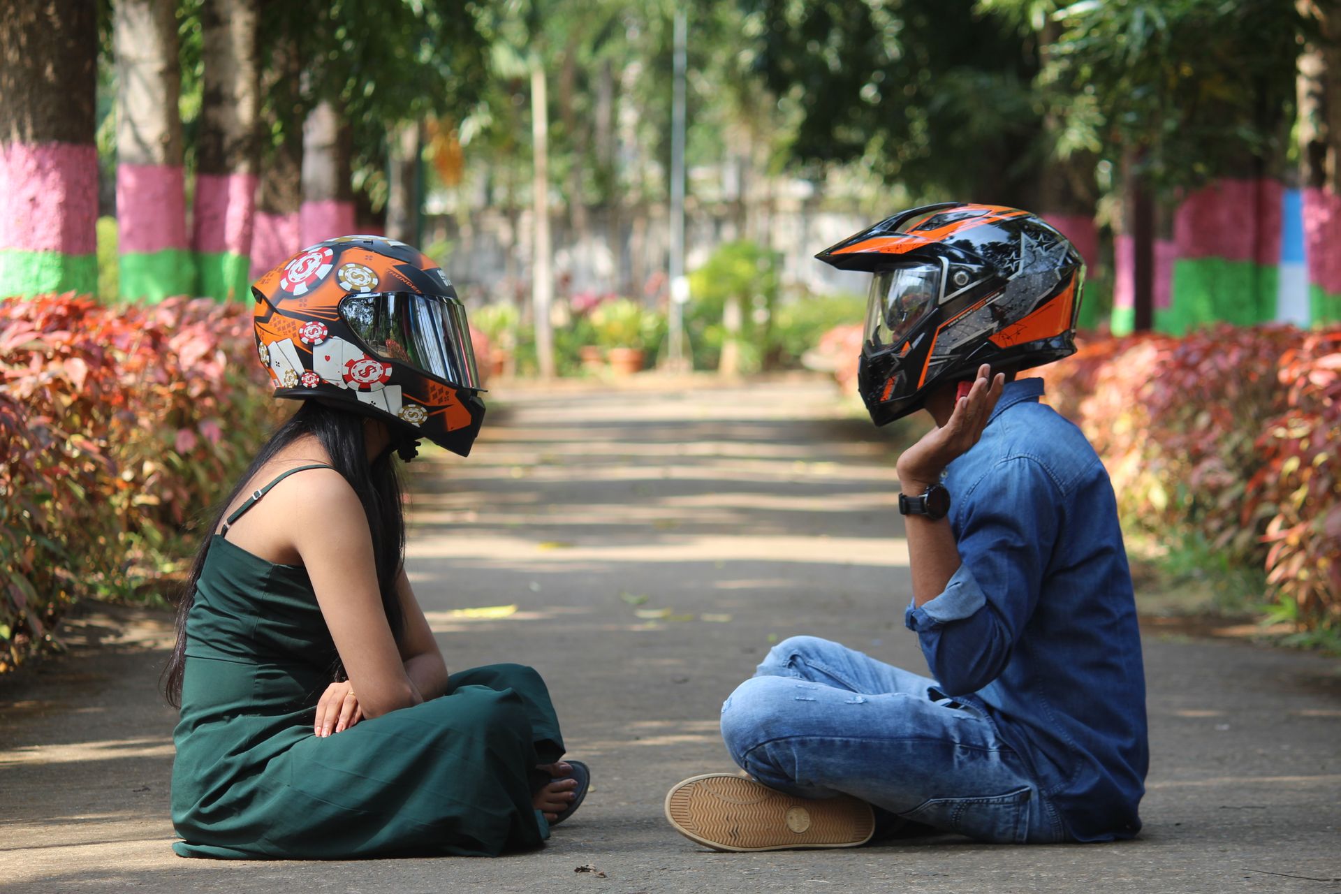 Couple with helmets sitting and talking in a colorful park setting, surrounded by nature.