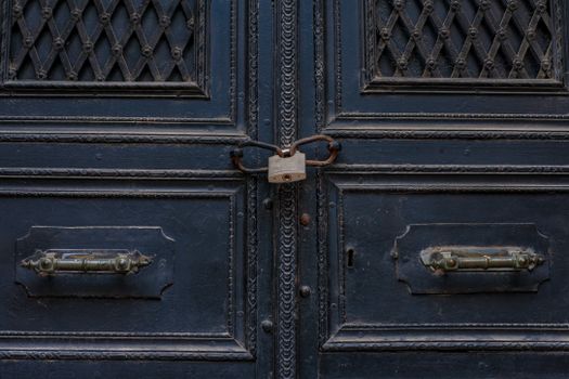 Close-up of a blue door with decorative patterns and a central padlock.