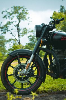 Front wheel of a Royal Enfield motorcycle on a scenic outdoor path in Kondagaon, India.