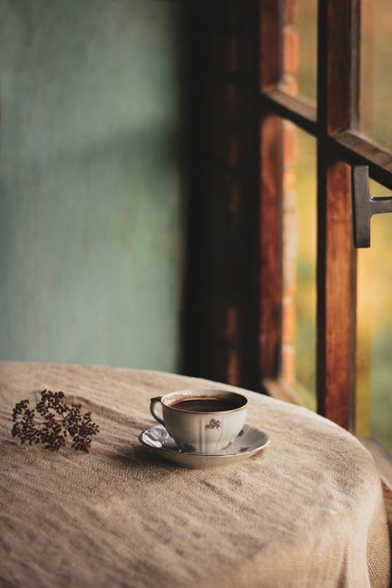 A cozy coffee cup sits on a rustic table by a sunlit window, creating a serene and warm atmosphere.
