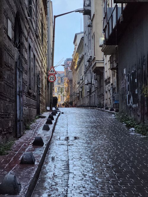 Free A deserted narrow street with wet cobblestones and old buildings on a rainy day in the city. Stock Photo