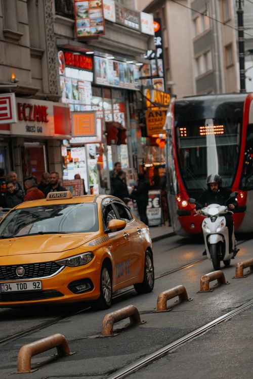 Free Vibrant street scene in Istanbul featuring taxi, tram, and motorbike in lively urban setting. Stock Photo
