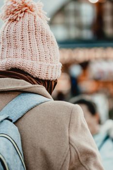 Woman in a stylish knitted beanie and coat strolling outdoors in winter.
