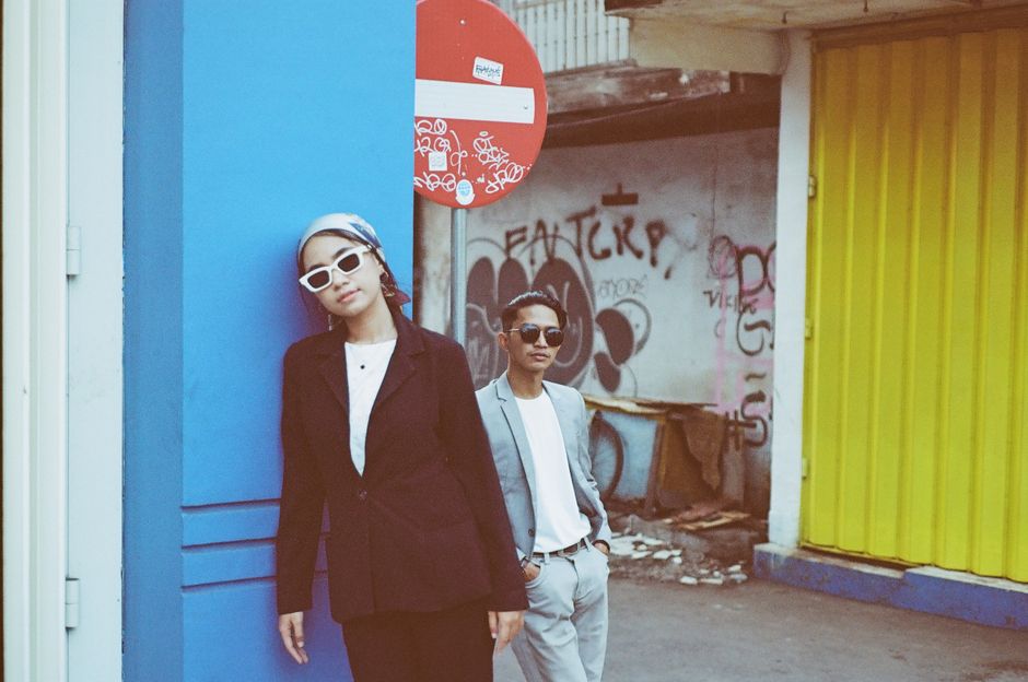 Two stylish individuals posing in an urban setting with vibrant graffiti.