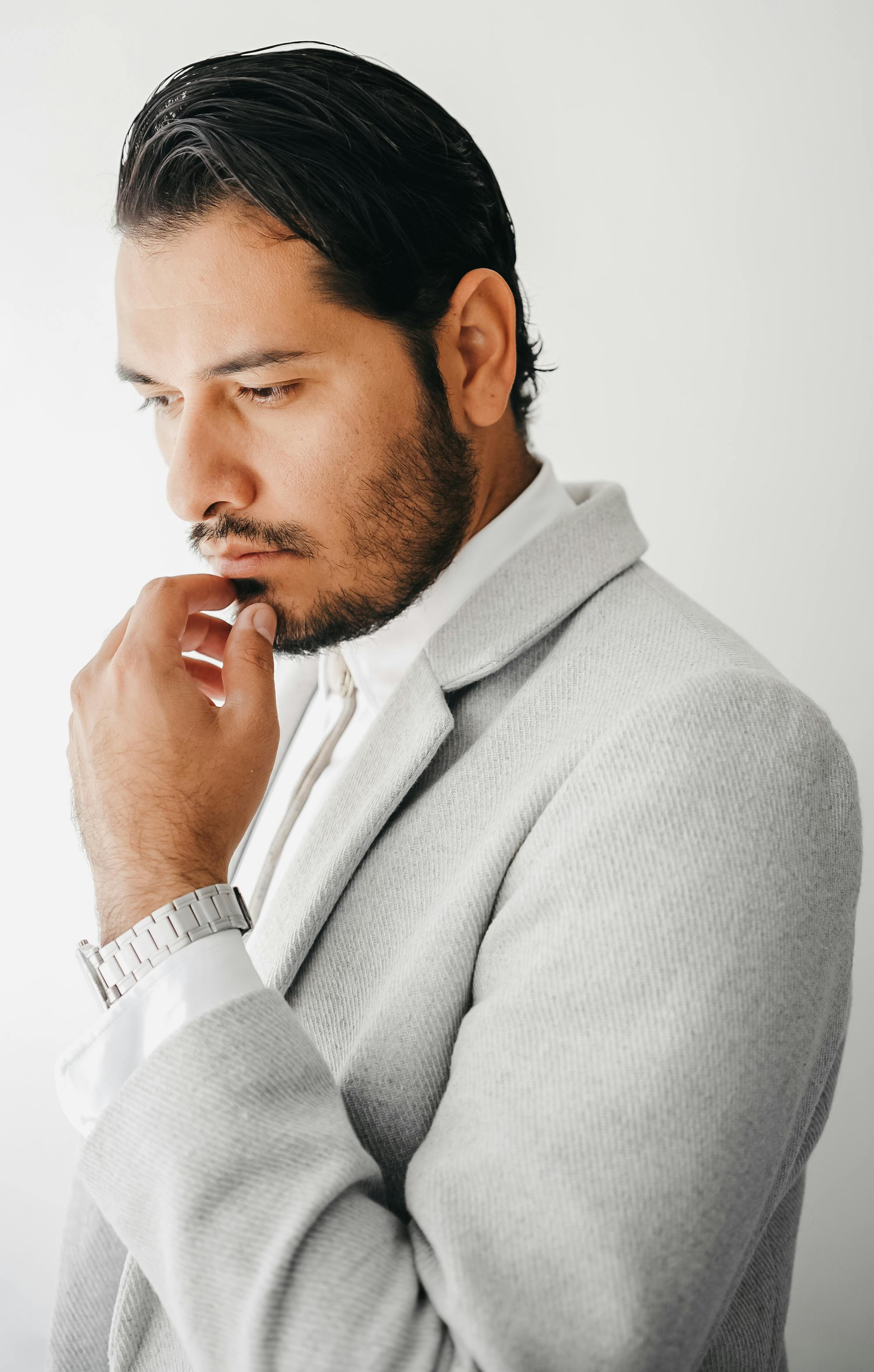 A contemplative man in a gray suit posed elegantly, exuding a fashion-forward style with minimalist elegance.