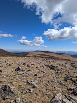 A breathtaking view of a rocky mountain landscape under a bright blue sky with scattered clouds.
