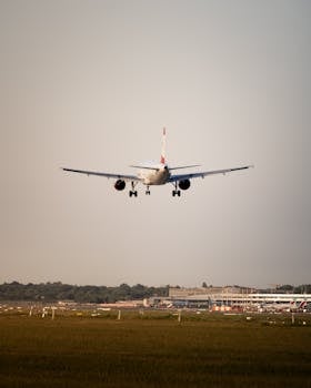 A passenger jet approaches its landing on a runway against a clear sky.
