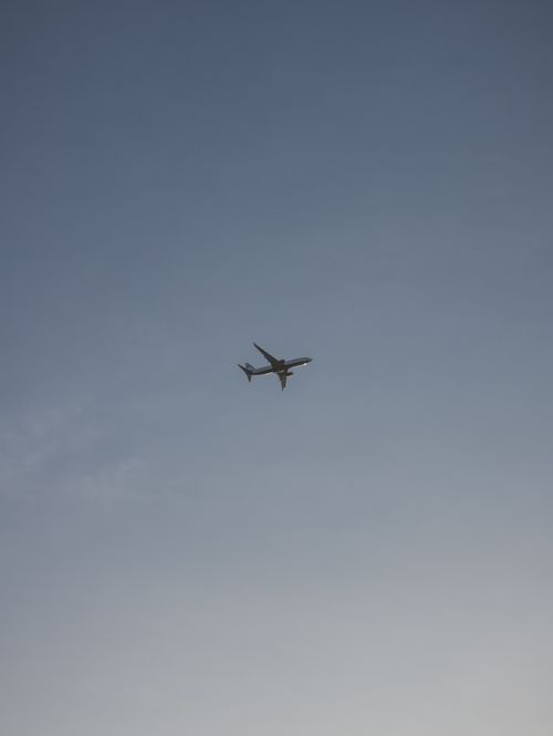 Free A commercial airplane soaring across a clear blue sky, captured in flight. Stock Photo