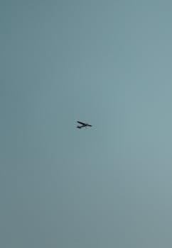 A small aircraft flying amidst a clear blue sky, symbolizing freedom and adventure.