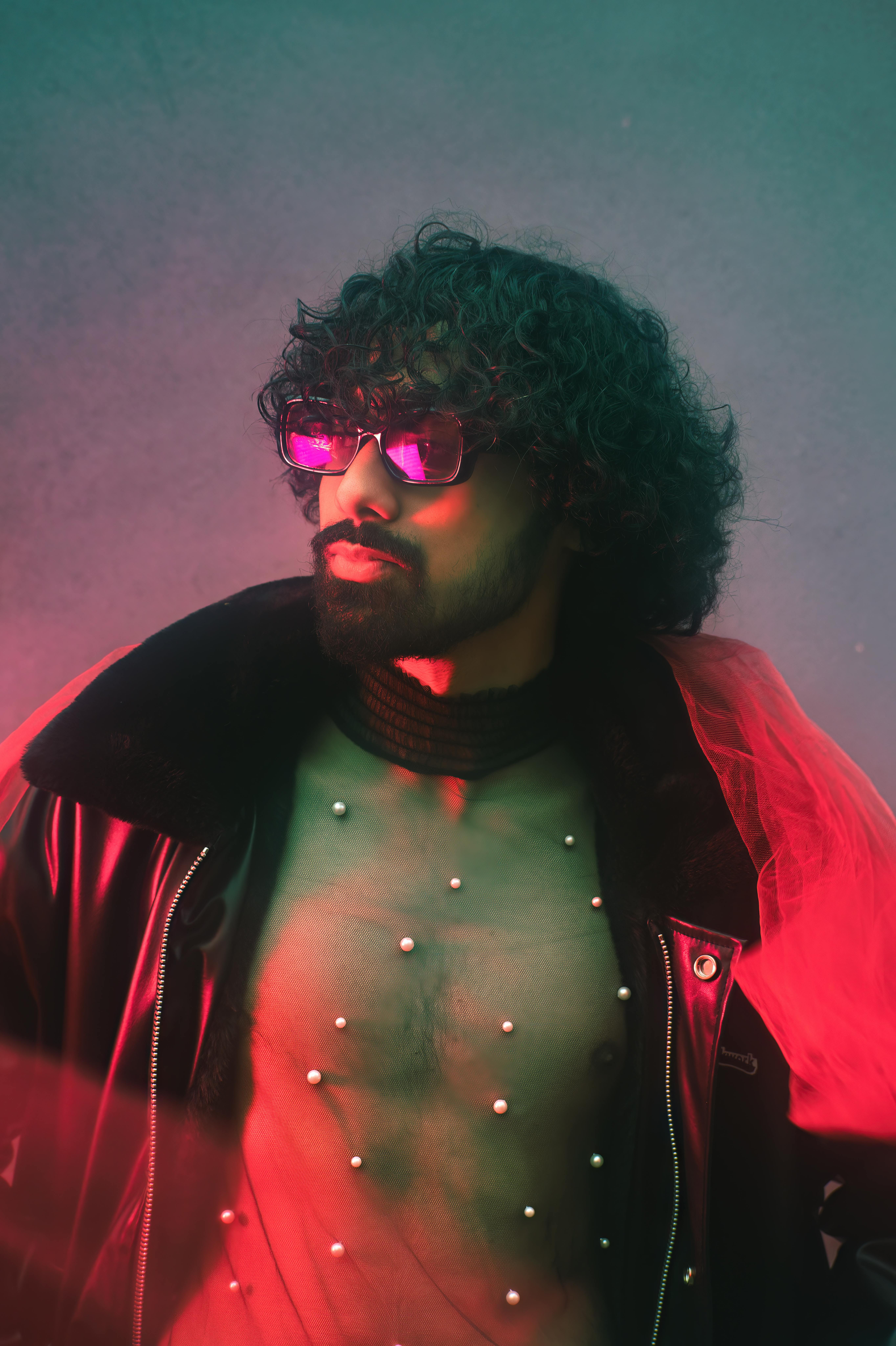 Stylish young man in avant-garde outfit with red lighting accentuating his fashion-forward look.