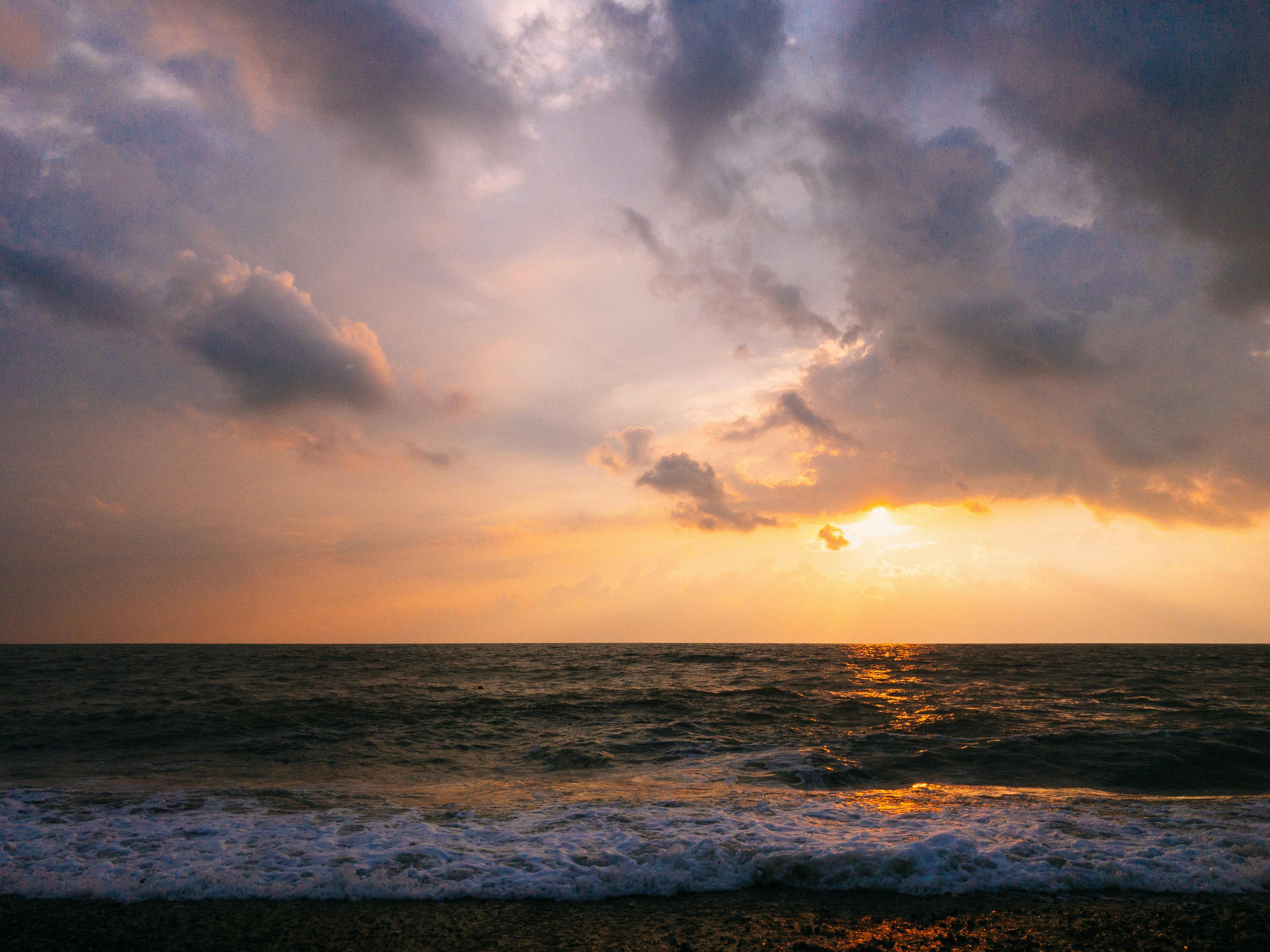 A stunning sunset view over the Black Sea in Tuapse, Russia, showcasing dramatic clouds and golden reflections.