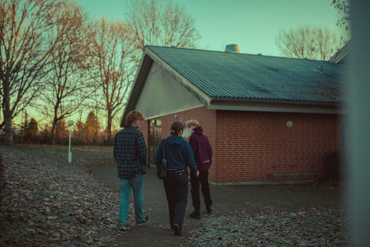 People Walking On Paved Path Near A Brick Building