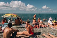 在俄罗斯索契的鹅卵石海滩上，人们悠闲地放松和享受日光浴，呈现出一派充满活力的景象