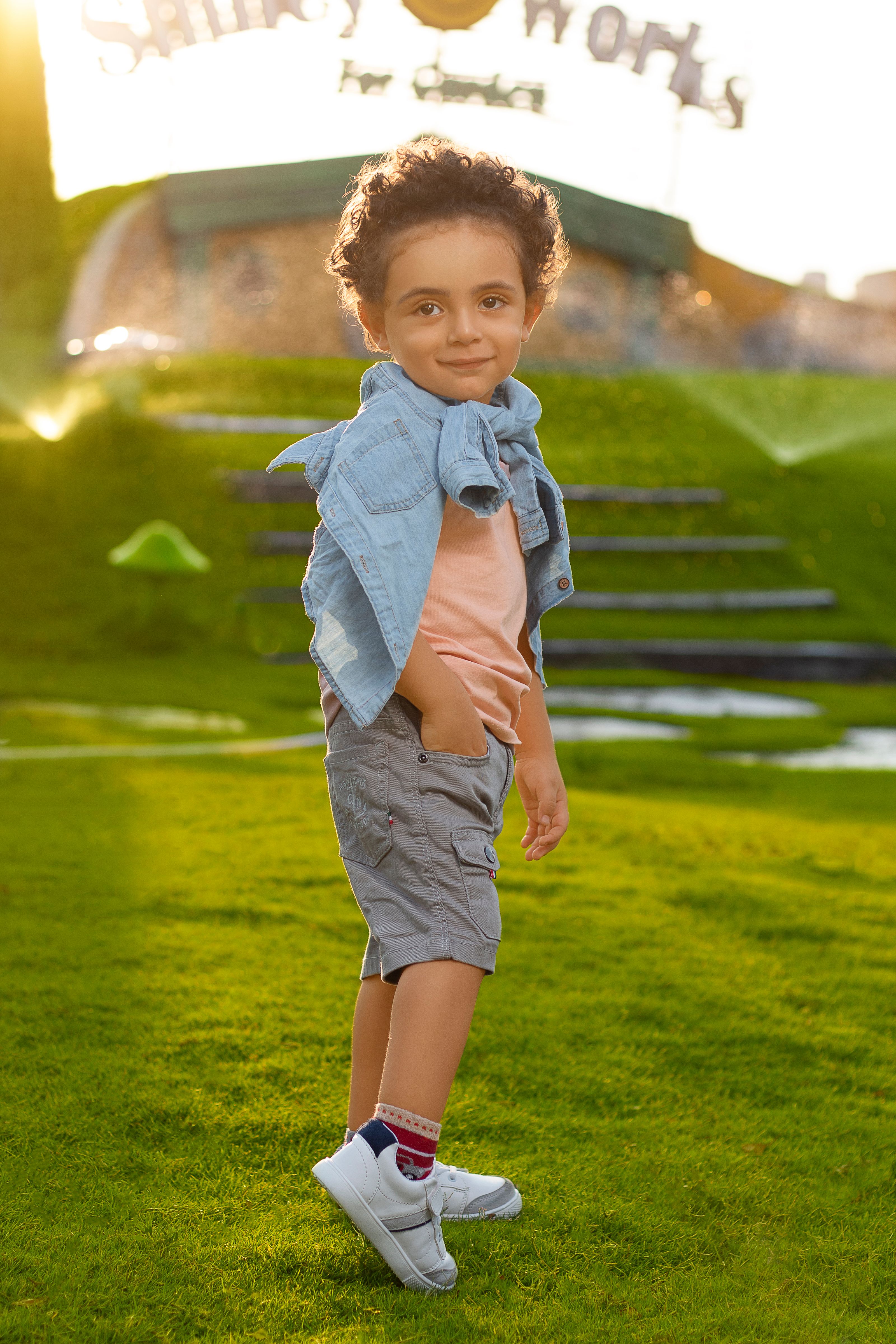 Retrato ao ar livre encantador de um jovem menino sorrindo ao sol, desfrutando de um dia relaxante na grama.