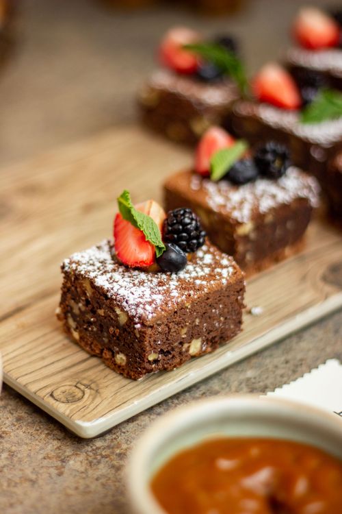 Free Close-up of chocolate brownies topped with strawberries and blackberries on a wooden tray. Stock Photo