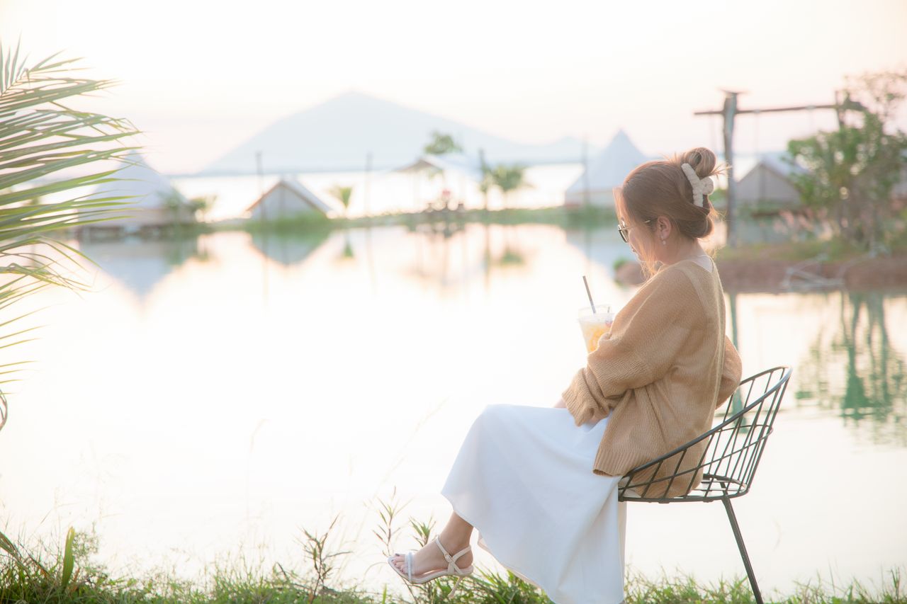 a woman enjoys a tranquil moment by the lakeside sipping a drink
