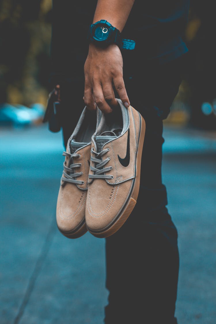 Person Holding Pair Of Brown Nike Sneakers