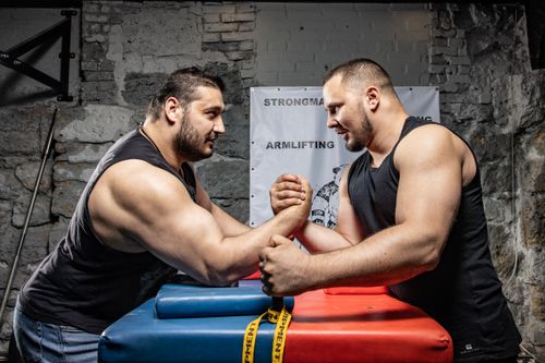 Free Two muscular men engaged in a competitive arm wrestling match in a gritty industrial environment. Stock Photo