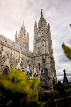 Stunning view of the iconic Gothic Basilica del Voto Nacional in Quito, Ecuador with cloudy sky.