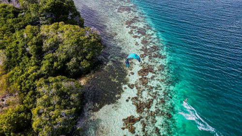 Free Aerial shot of a kite surfer navigating vibrant blue waters along the lush Venezuelan coastline. Stock Photo