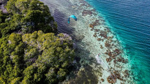 Free Drone shot of kitesurfing near lush island shores in Venezuela. Stock Photo