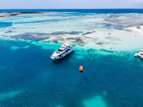 Aerial view of a yacht and kitesurfer in a turquoise tropical lagoon. Perfect for travel and adventure themes.