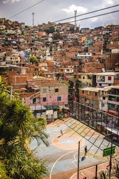 Aerial view of a colorful basketball court amidst the dense favelas of Medellín, Colombia.